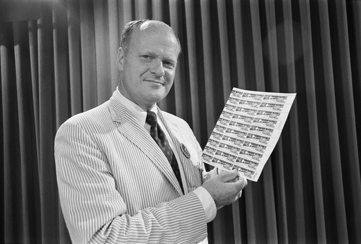 Image of Robert McCall holding the Apollo 15/Decade of Achievement commemorative stamp sheet, Scott Cat. Nos. 1434 and 1435